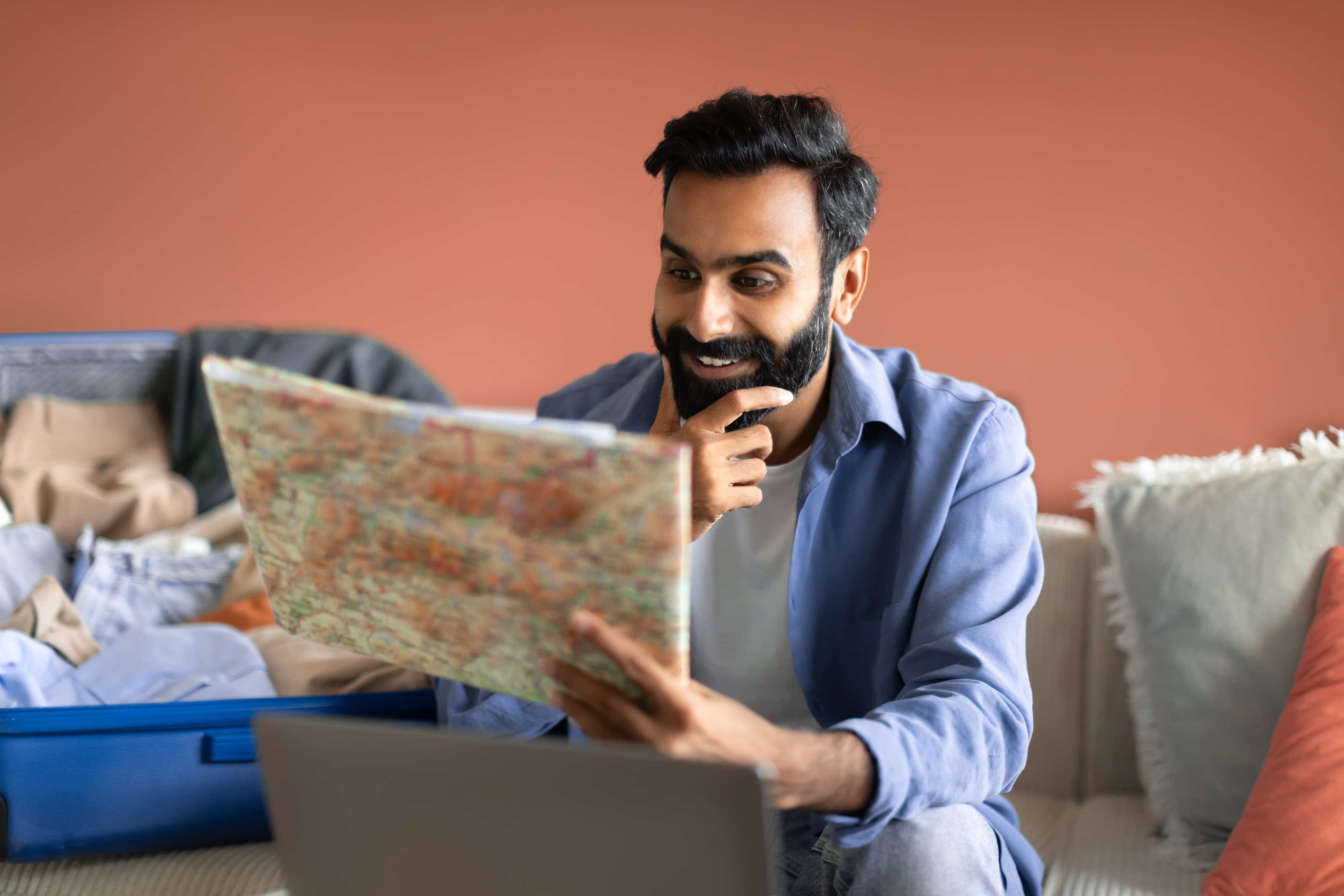 Traveler planning a trip with a map, laptop, and packed suitcase